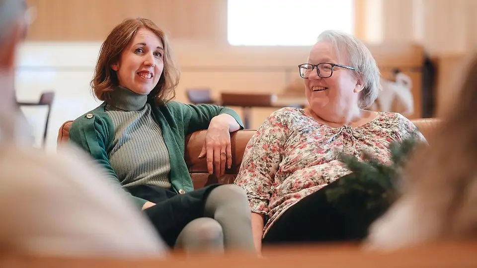 Två kvinnor sitter i en soffa och pratar.